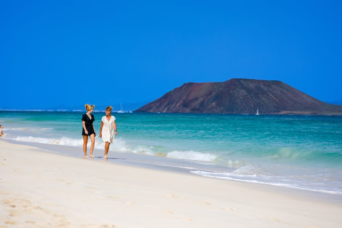Women walking down beautiful beach in Corralejo, Spain